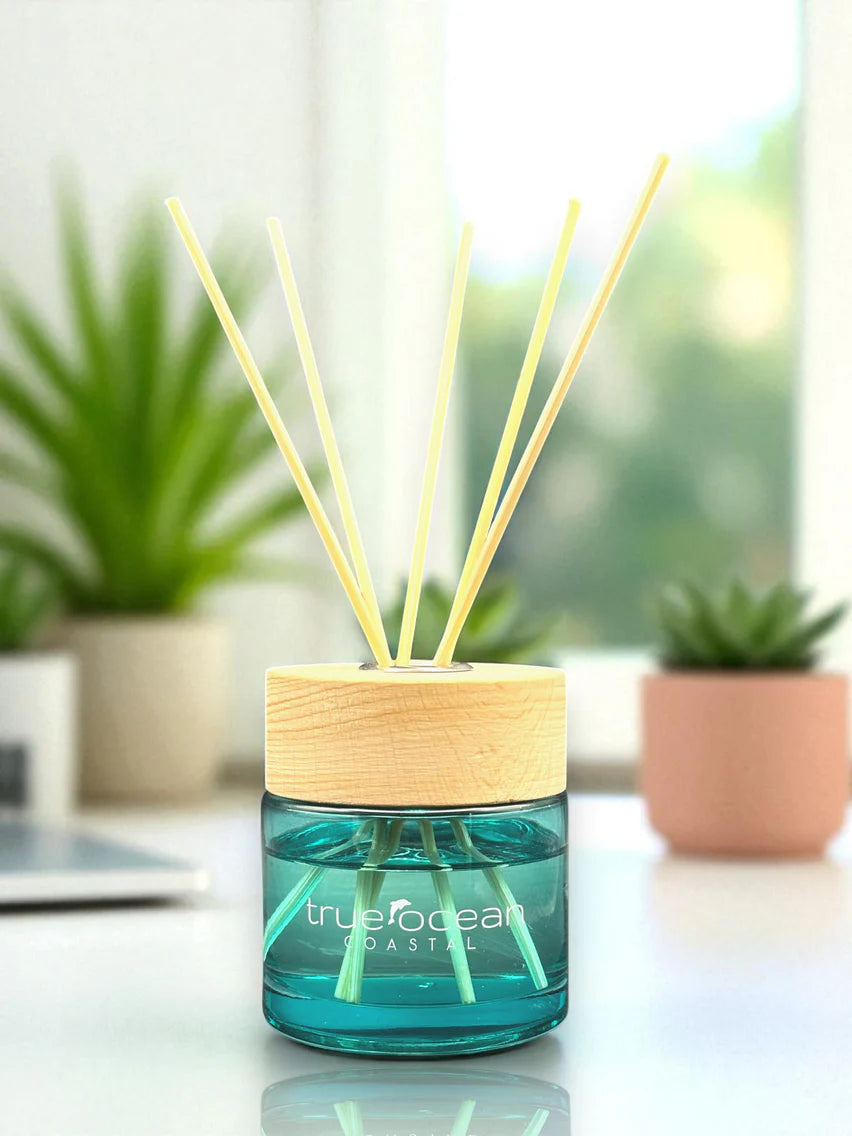 Reed diffuser with wooden cap and green bottle on a blurred indoor background